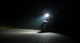 Farol de milha em moto pequena iluminando estrada à noite