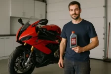 Homem segurando óleo ideal para motos esportivas ao lado de moto vermelha em oficina