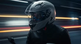 Motociclista usando capacete fechado em estrada, simbolizando segurança e proteção